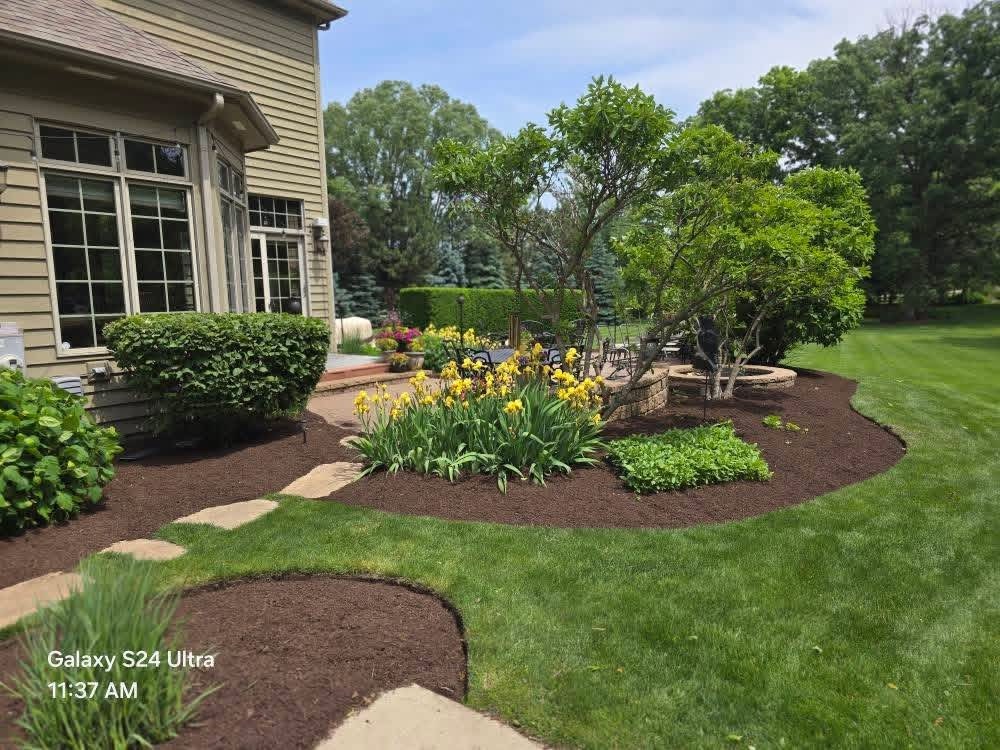 Flower beds and fresh mulch beside a backyard patio